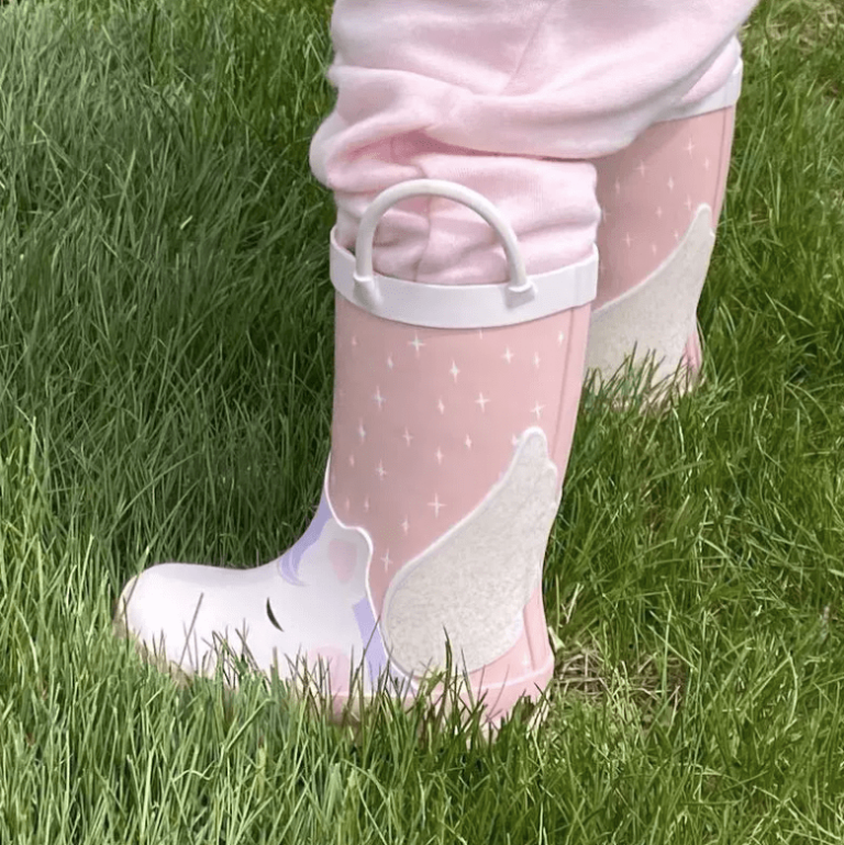 cute toddler in unicorn rain boot and pink pants outdoors