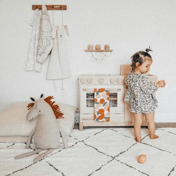 little girl playing with non toxic wood play kitchen