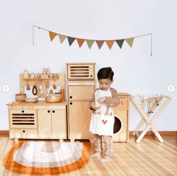 asian boy playing at non toxic wood play kitchen 