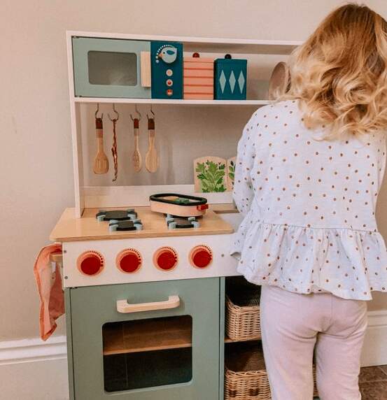 toddler girl playing with non toxic aesthetic play kitchen