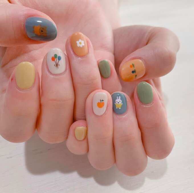 short round nails with yellow, orange, blue, and white easter designs