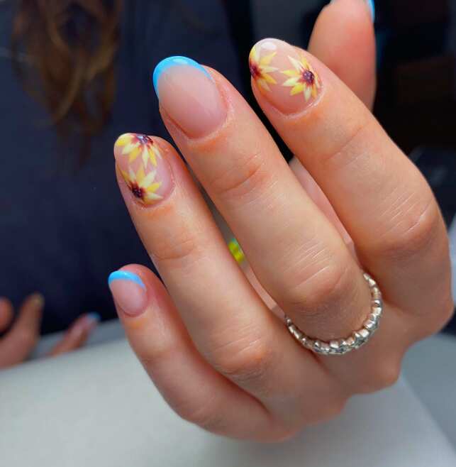short nails with thin blue french tips and yellow sunflowers