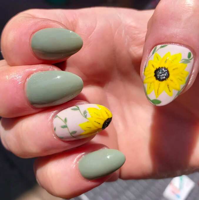 oval nails with sage green nail polish and sunflower art design