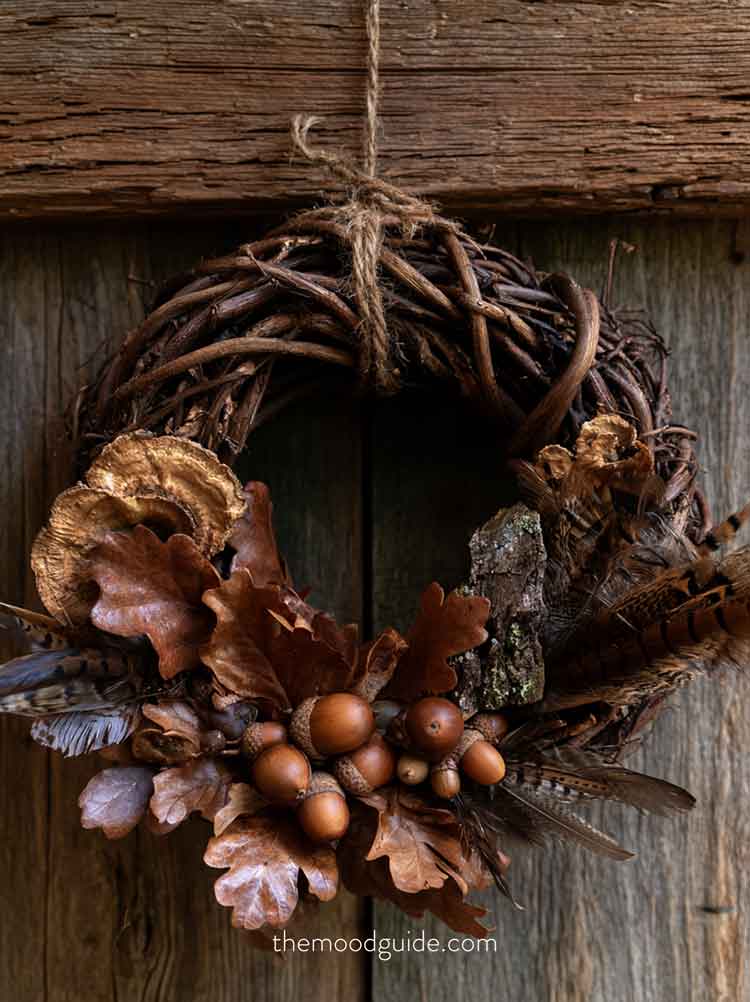 brown rustic fall wreath. The wreath is uniquely structured from thick, twisted wild grapevines, dried bracket fungi, rich brown acorns and oak leaves, pieces of natural tree bark, and wild pheasant feathers, tied with a simple piece of raw twine. 