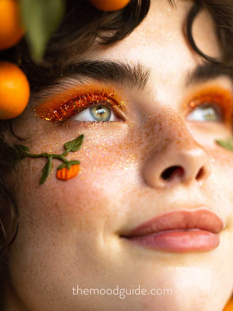 whimsical glittery fall halloween pumpkin makeup with orange glittery lashes